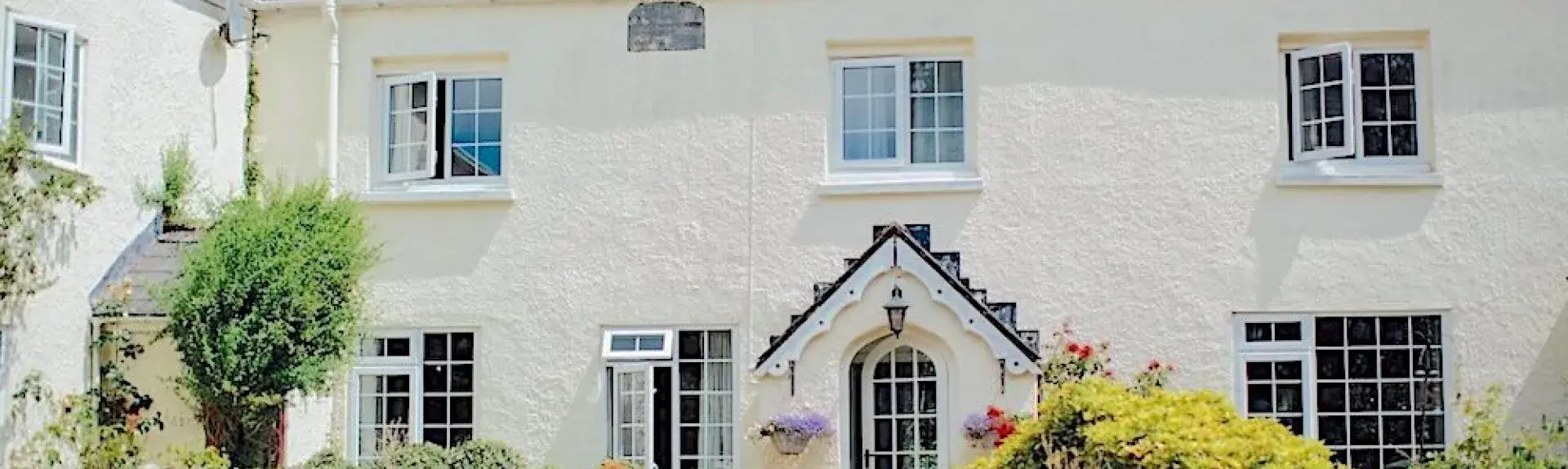 Large Exmoor farmhouse with cottage windows and a covered porch sits behind a walled front garden.