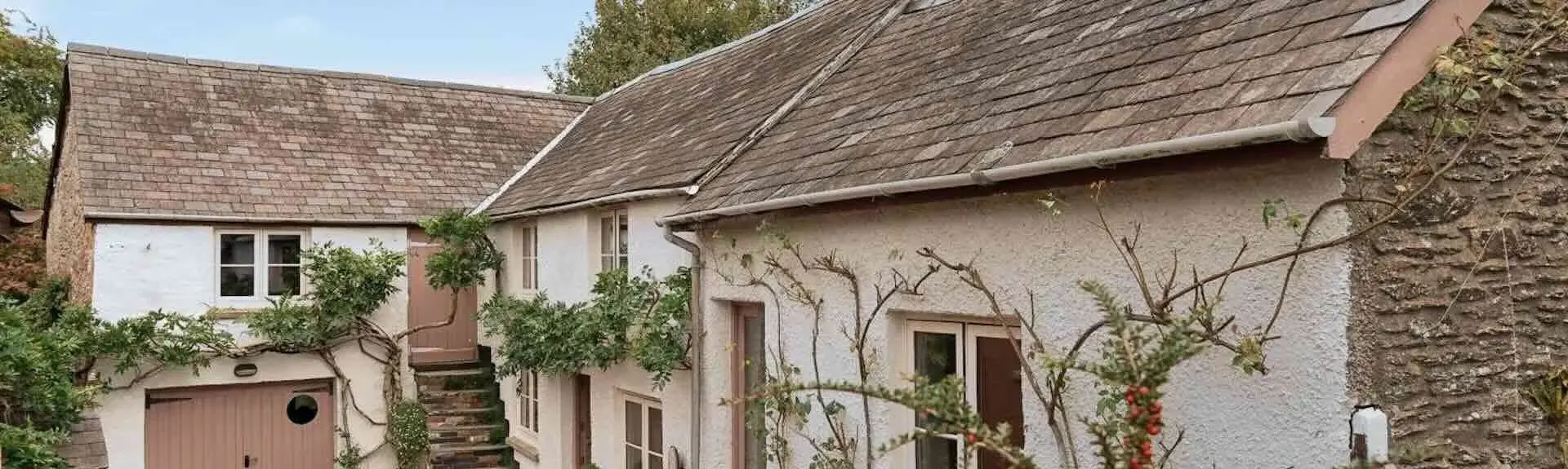 A semi-detached house with a shrub-filled front garden and privet hedge.
