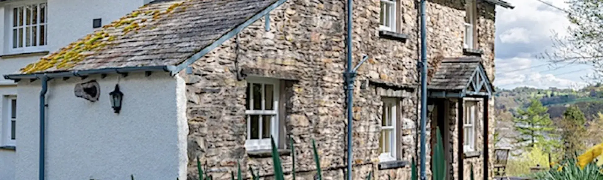 Front exterior of a stone-built countryside house and garden.
