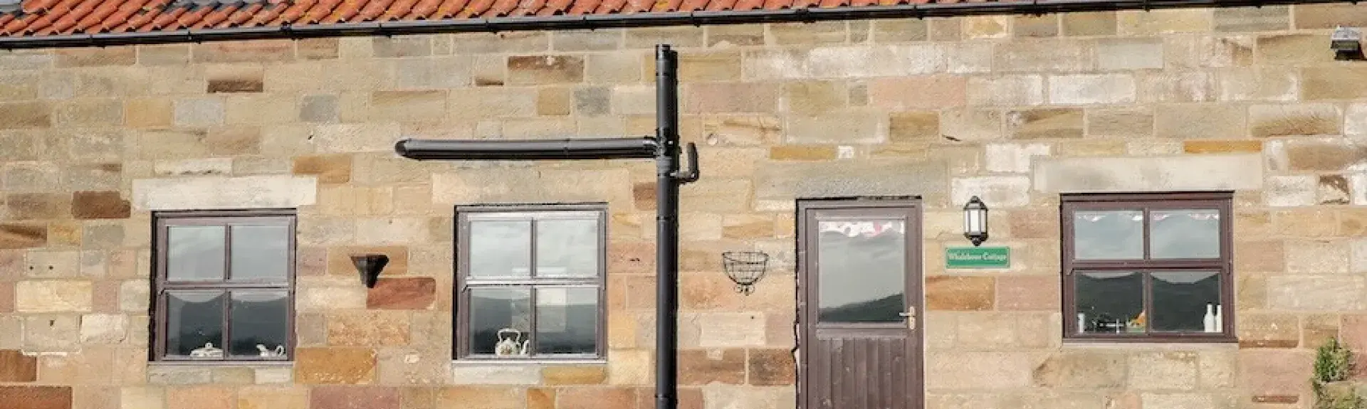 Stone built Whitby holiday home with terracotta tiles and Velux windows on the roof overlook a lawn and parking space