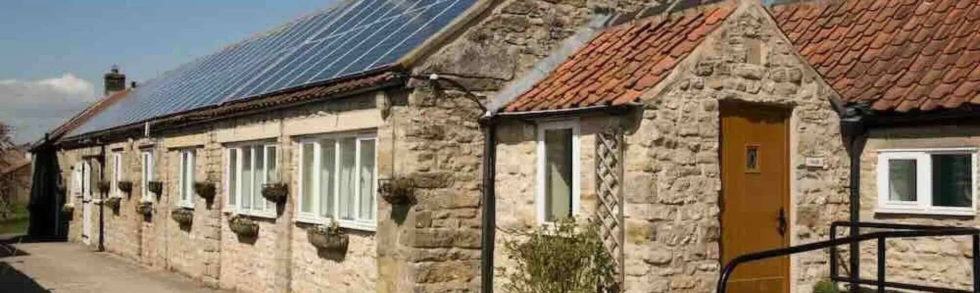 Exterior of a long, many-windowed barn conversion to form a single-storey holiday cottage in Pickering.