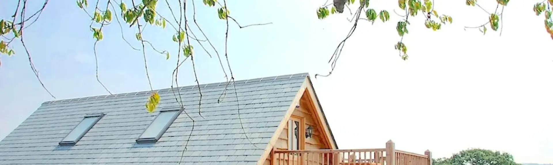 A Swiss-style wooden holiday lodge with a 1st floor deck looks out across lush Somerset countryside.