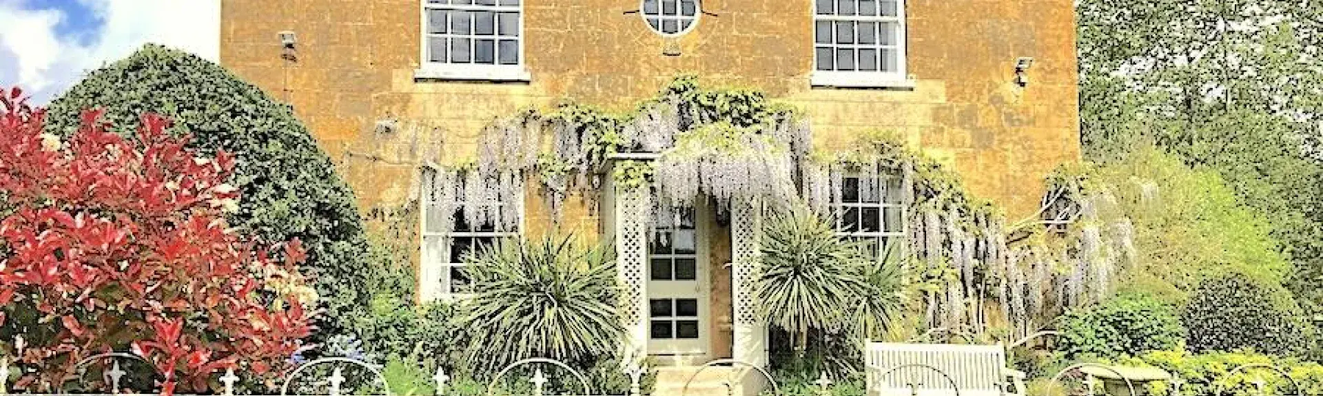 Exterior of a wisteria-clad, double-fronted Georgian House and front garden.