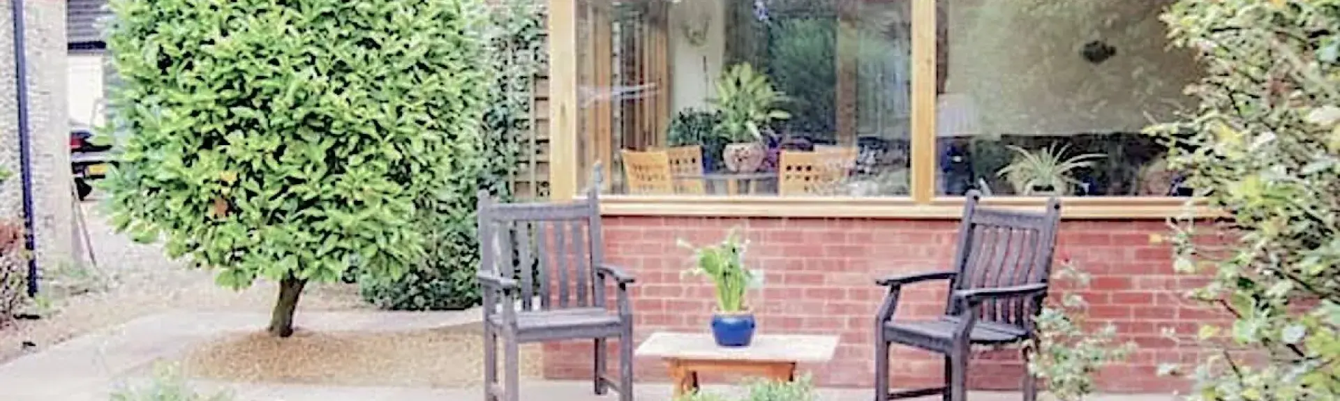 Exterior of a single storey Norfolk holiday lodge With a patio and lawn.
