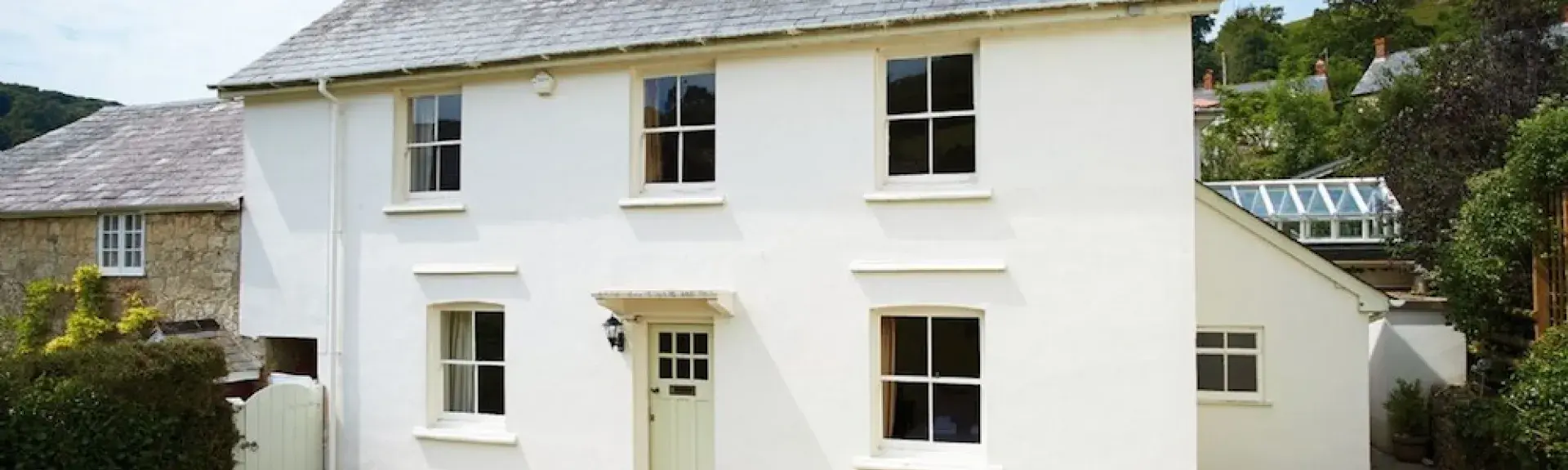A double-fronted East Devon holiday cottage in front of a secure lawned garden.