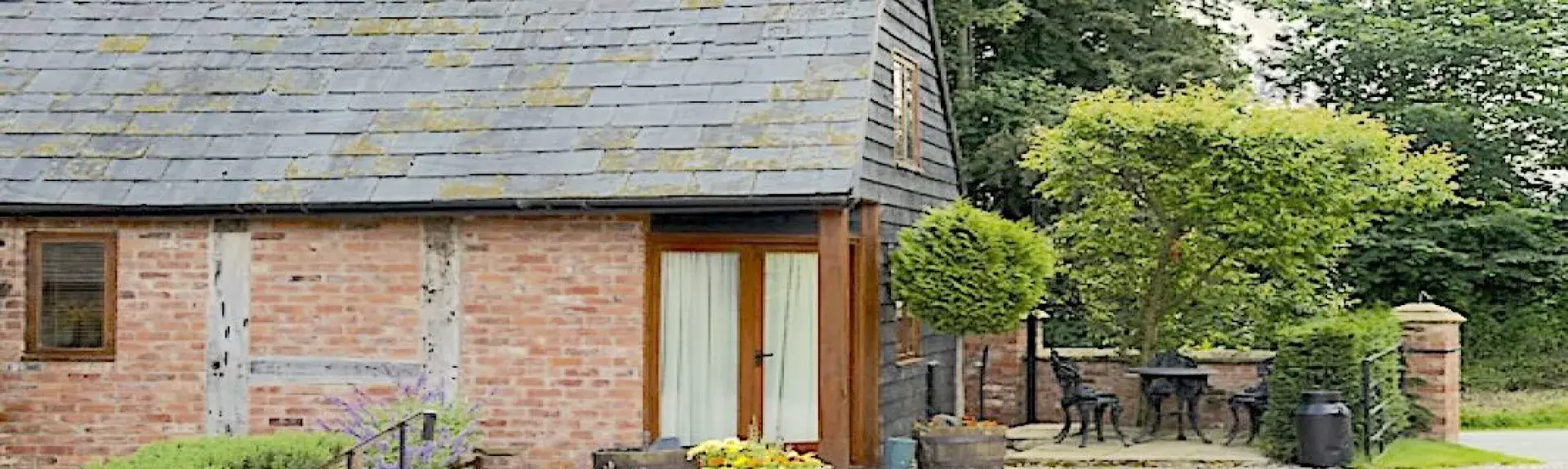 A Shropshire barn conversion with French windows and flower tubs in the shingled garden