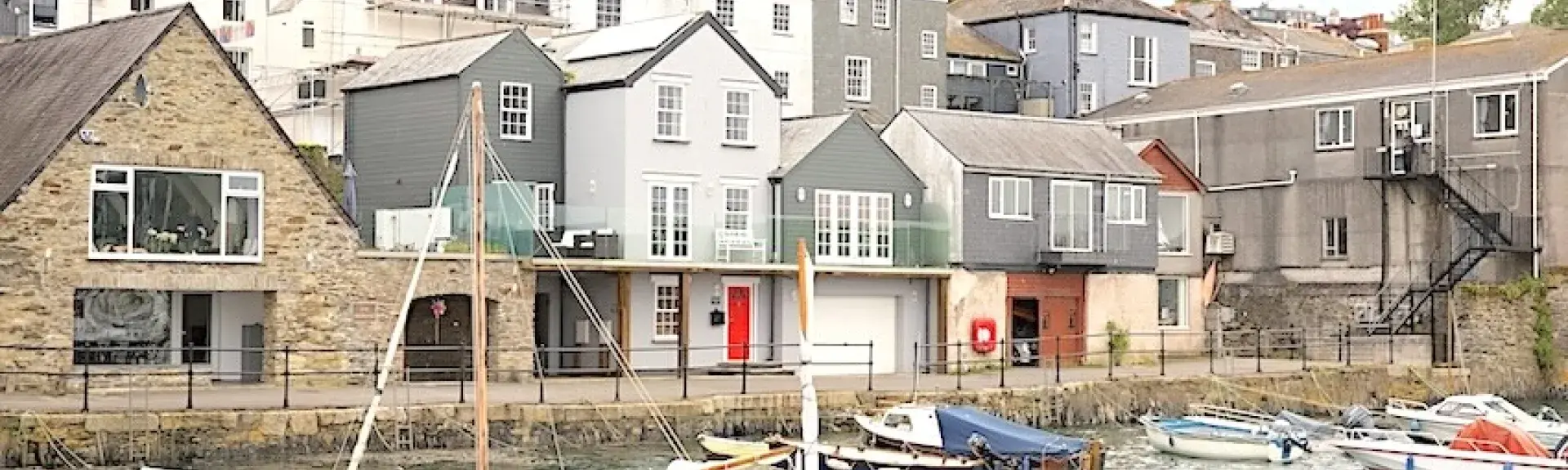 Former fishing lofts and fisherrmans cottages overlook a quayside with small craft moored in the harbour.