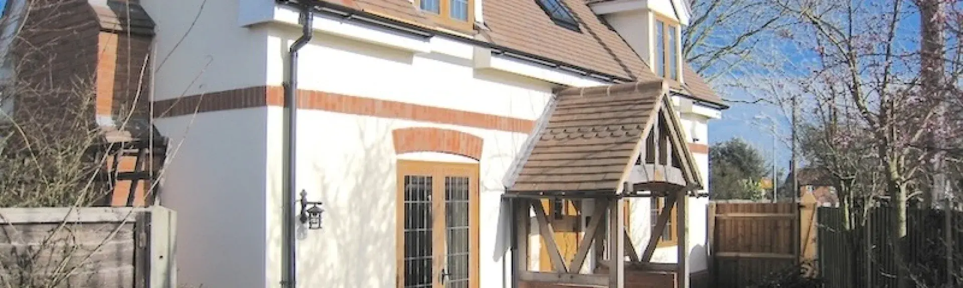 A double fronted modern chalet bungalow with a terraced garden behind a fence.