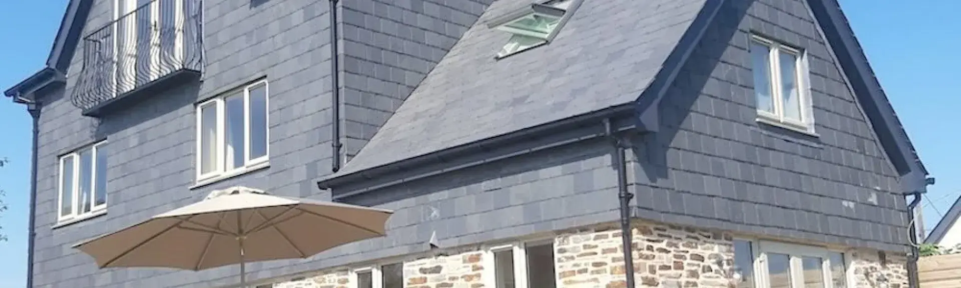 A large, 3-storey detached house built of stone with a 1st floor clad in slates.
