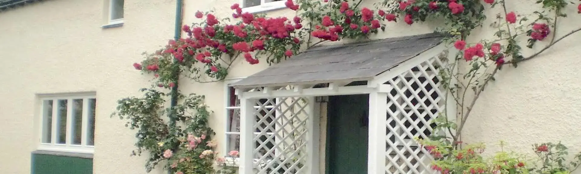 Climbing roses surround the porch of a country cottage in Somerset.