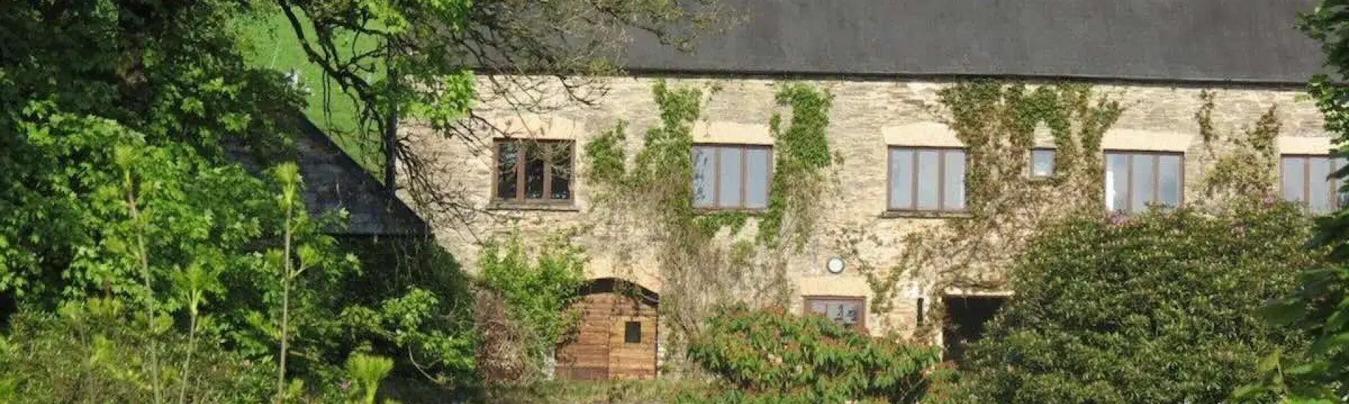 A country cottage with a backdrop of mature trees and a large front garden.