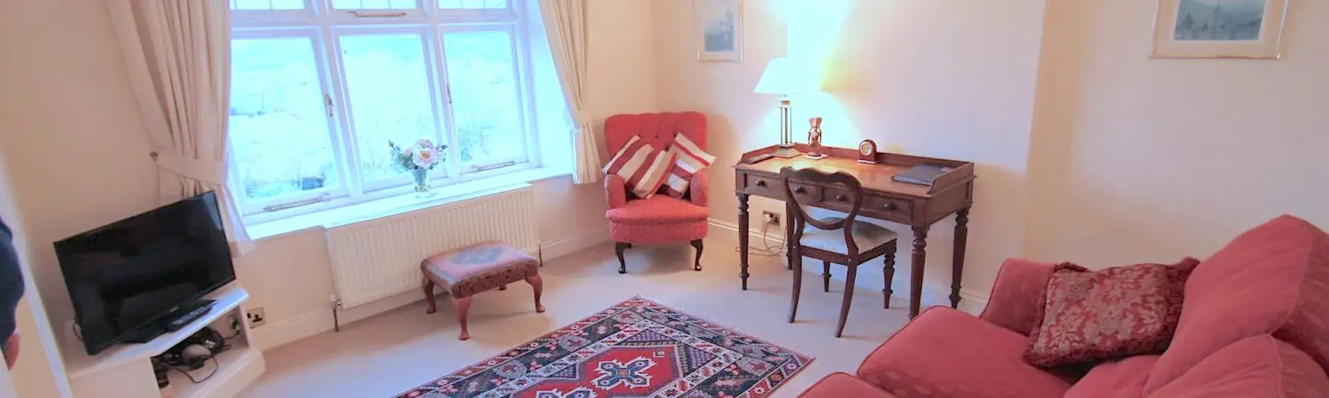 Somerset coastal apartment lounge for couples with a sofa, armchair, side table and TV.