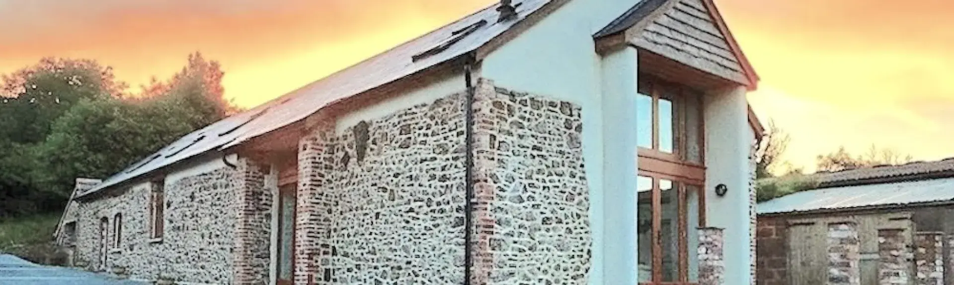 A Devon barn conversion with a deck at sunset.