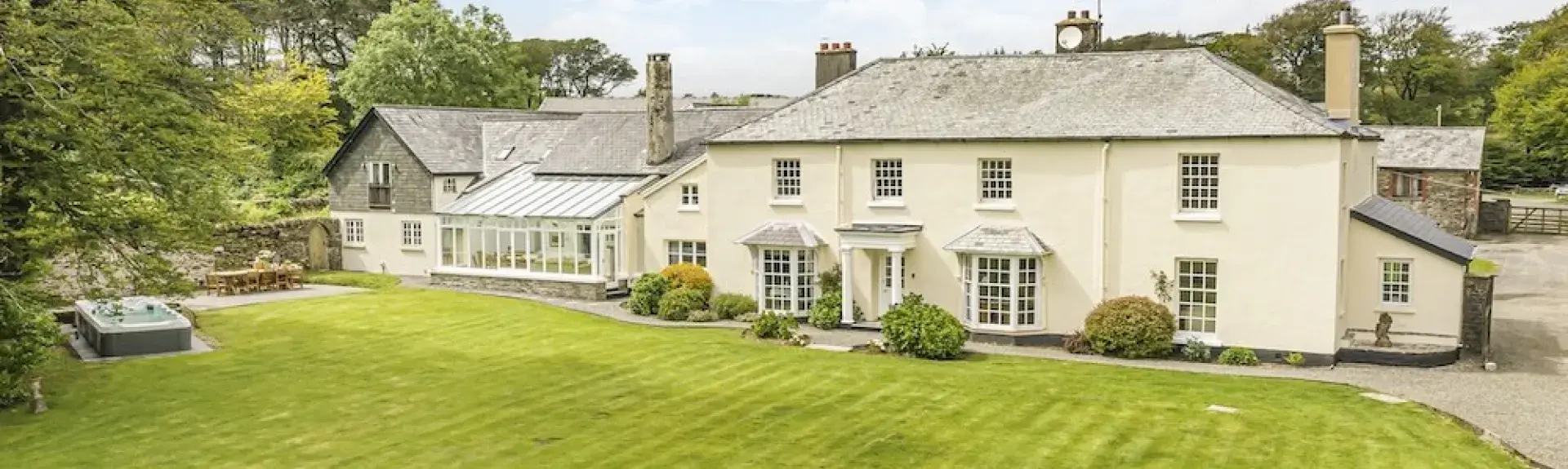 Exterior of a 2-storey country house on Exmoor overlooking a large lawn with a hot tub.