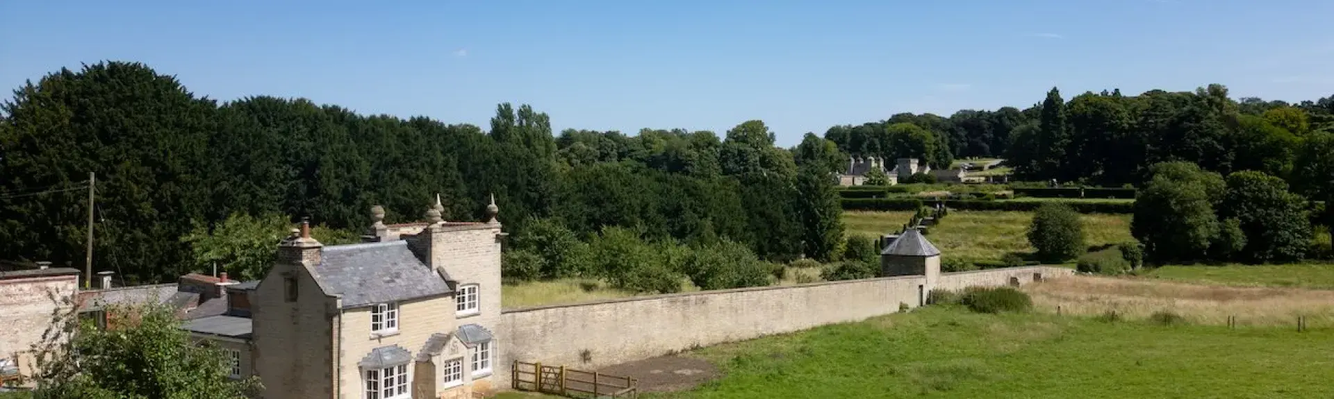 A 2-storey stone cottage attached to the edge of a walled garden.
