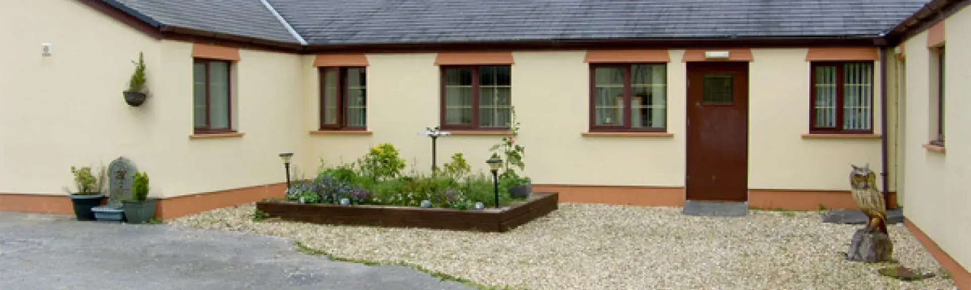 A single-storey barn conversion with right-angled wings faces a paved courtyard.