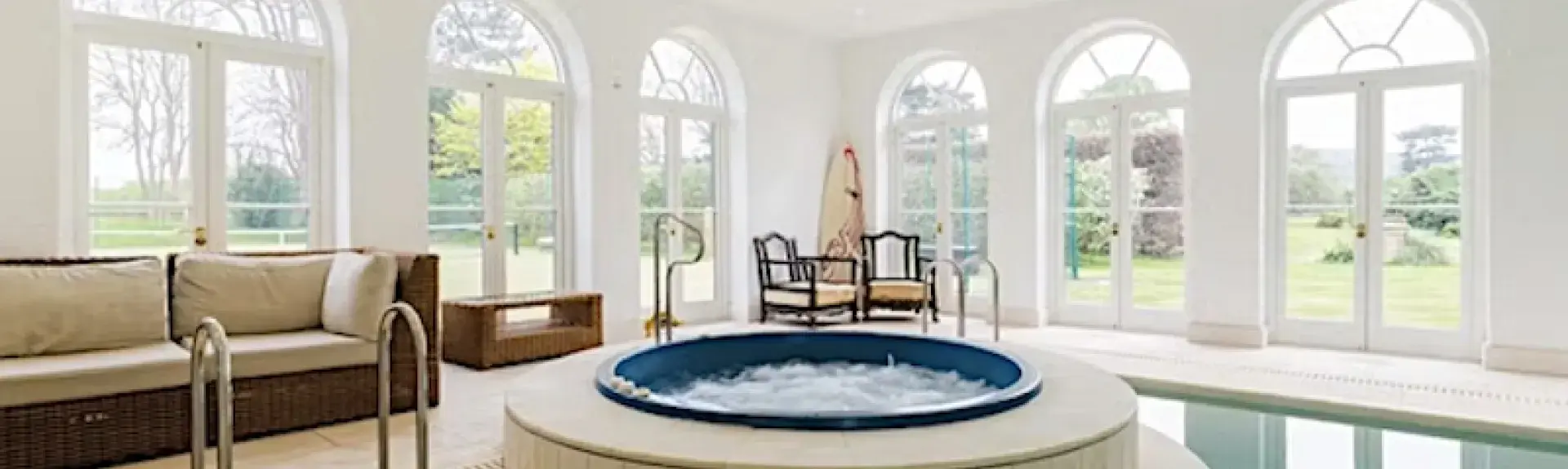 A jacuzzi sits within a large indoor swimming pool.