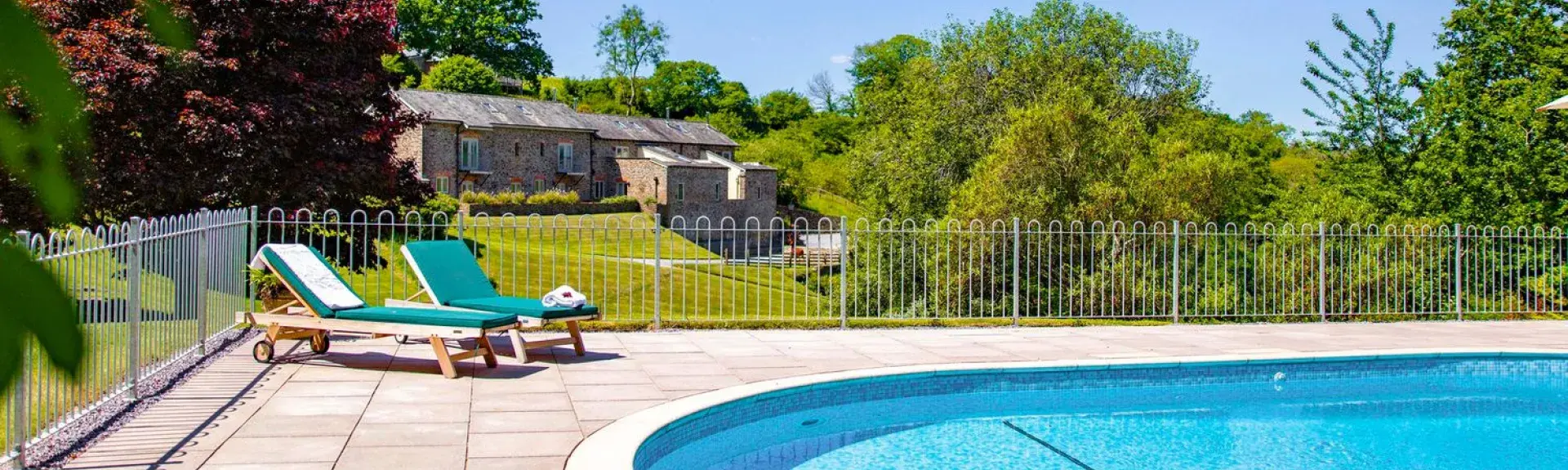 Outdoor swimming pool with table of drinks and snacks in front.