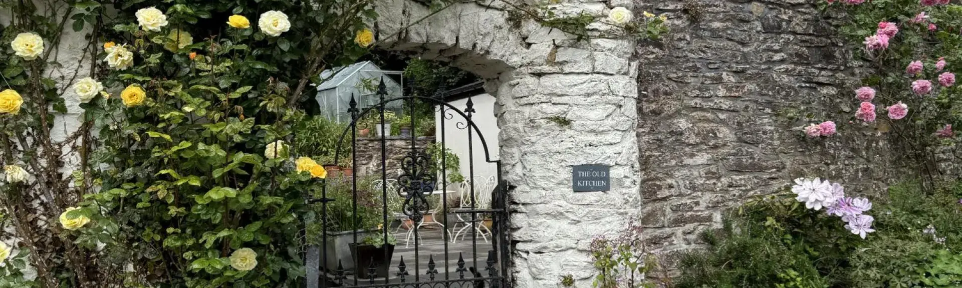An arch in a wall leads to a courtyard of an Exmoor holiday cottage.