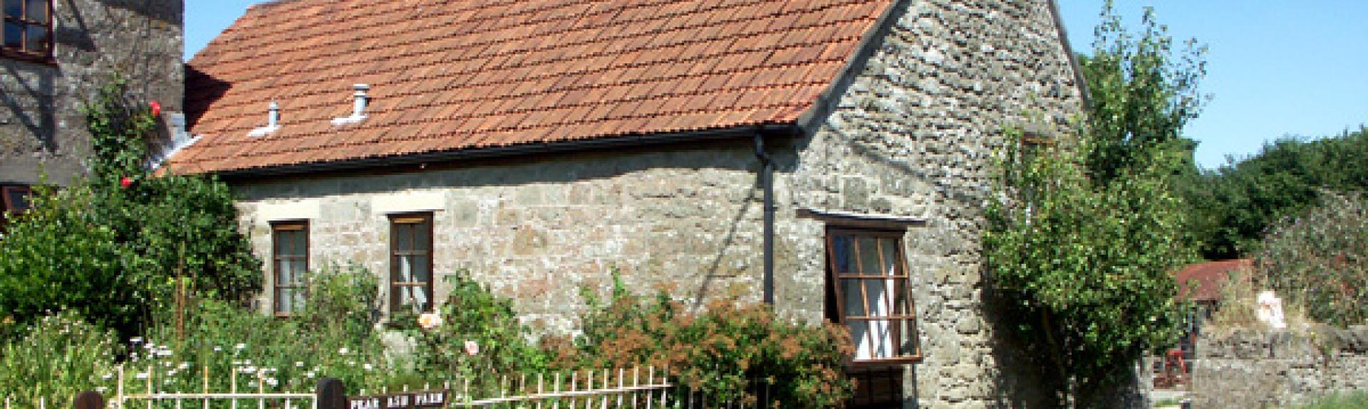 A stone-built somesret holiday cottage with a mature garden overlooks a quiet lane.