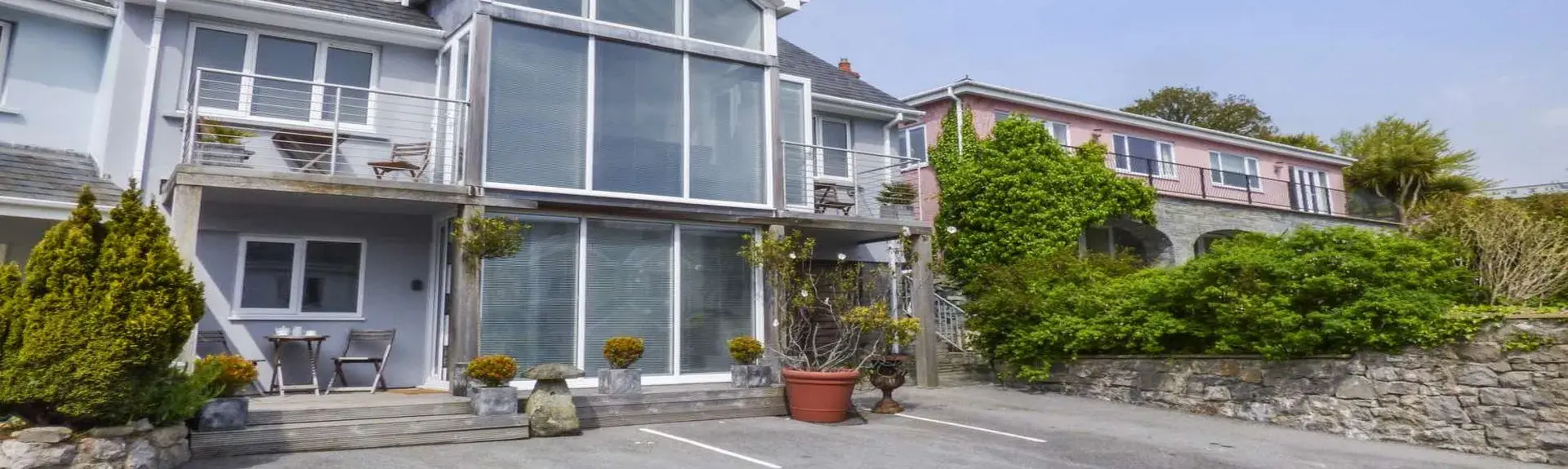 A large, contemporary 3-storey apartment building with a central gable of floor-to-ceiling windows.