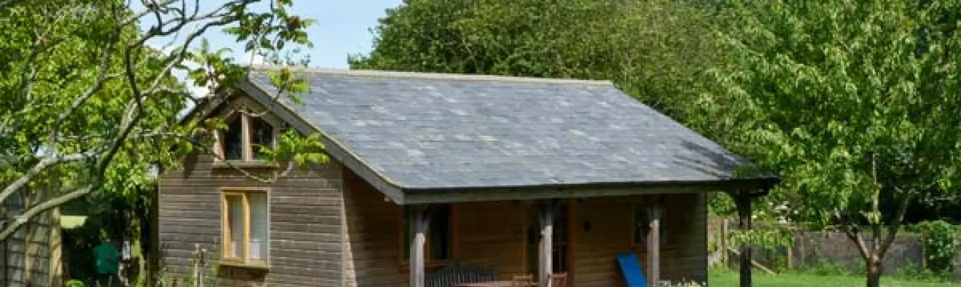 A single storey wooden barn conversion with an extended roof to create a sheltered terrace.