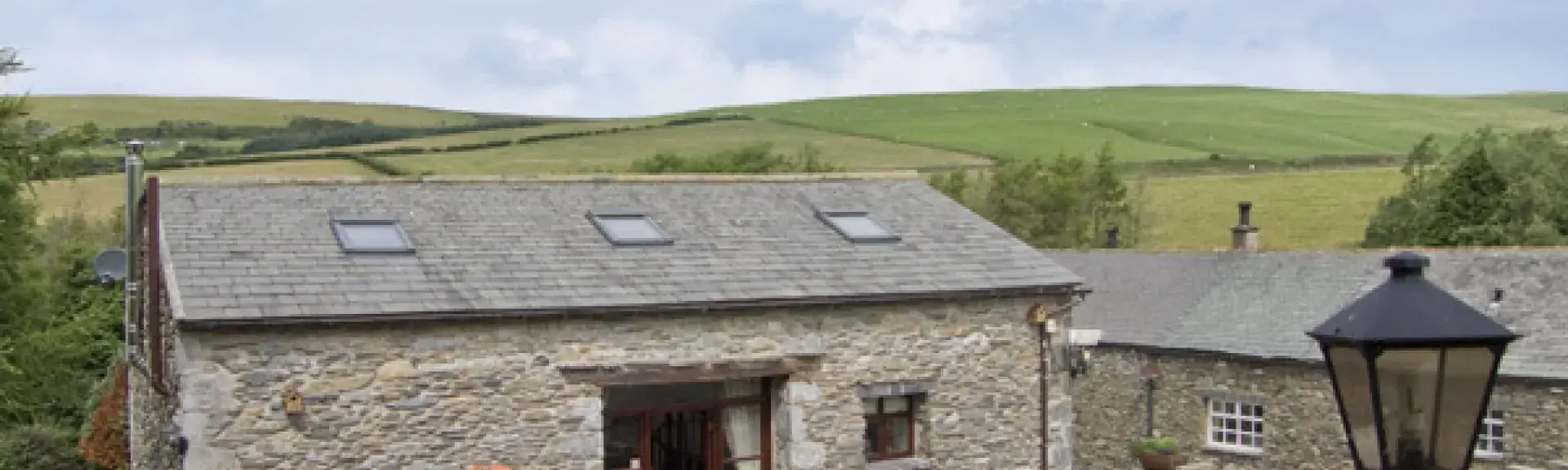 Front exterior of a stone-built barn conversion in Cumbria with a small, paved courtyard.