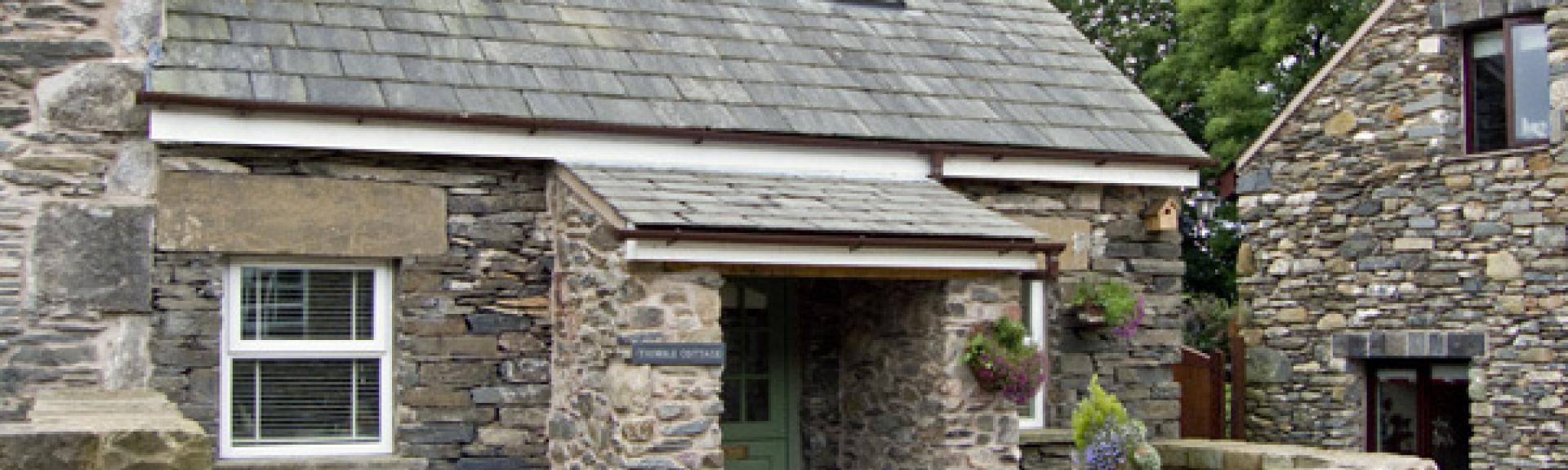 A 2-storey holiday cottage in Ulverston in a convrted stone barn surrounded by a low stone wall.