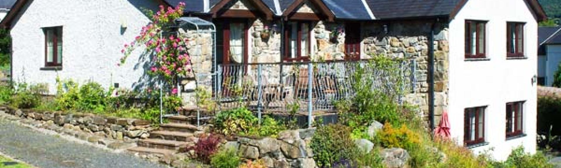 A large L-shaped Gwynedd holiday cottage house with a deck and rockery garden. garden.