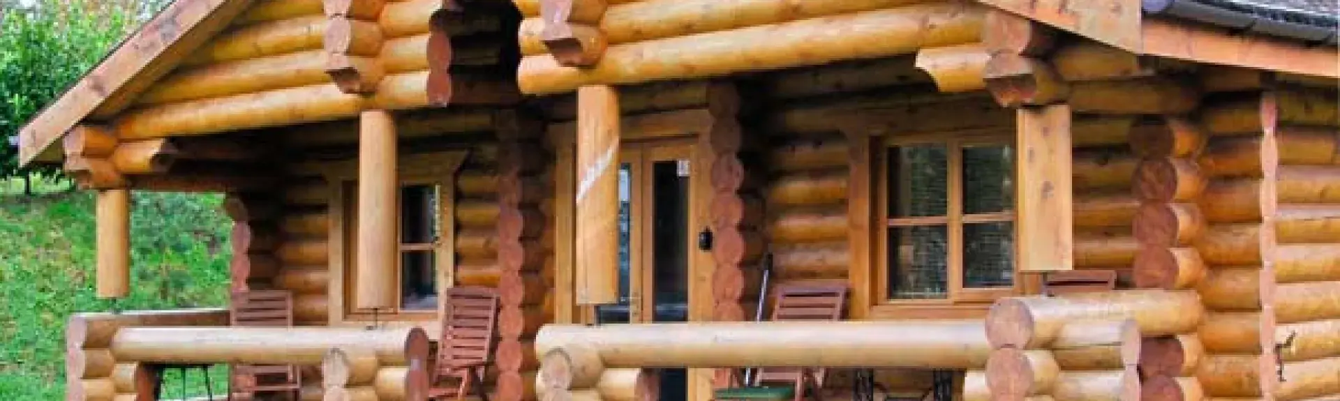 Front of a log cabin showing a covered deck.
