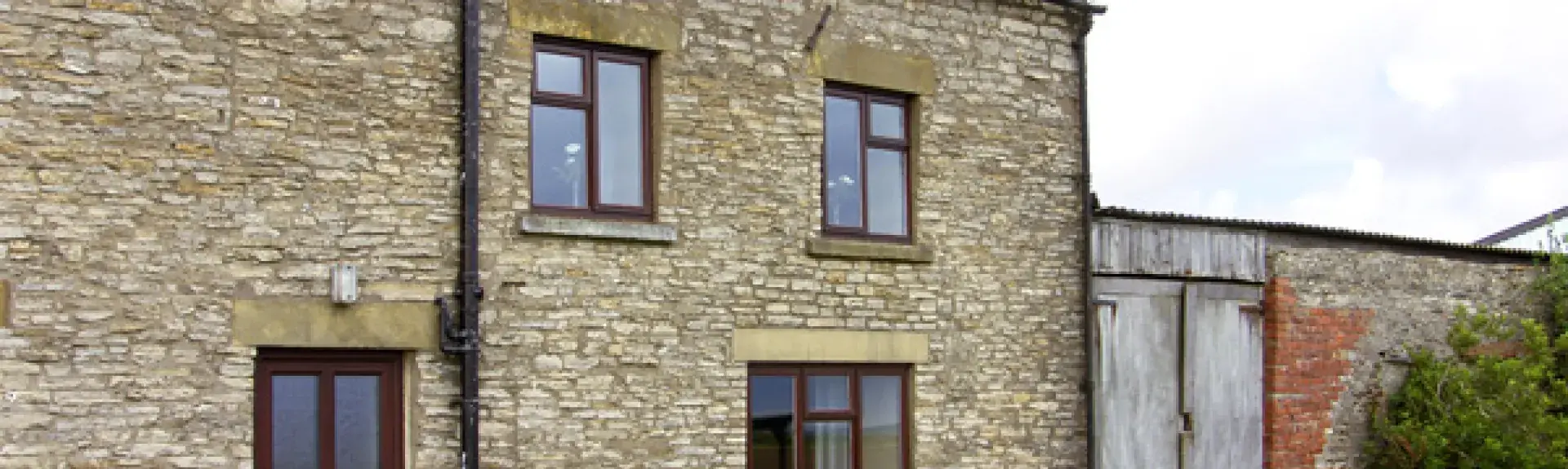 A stone-built, 2-storey holiday cottage in Helmsley overlooking a large lawn.