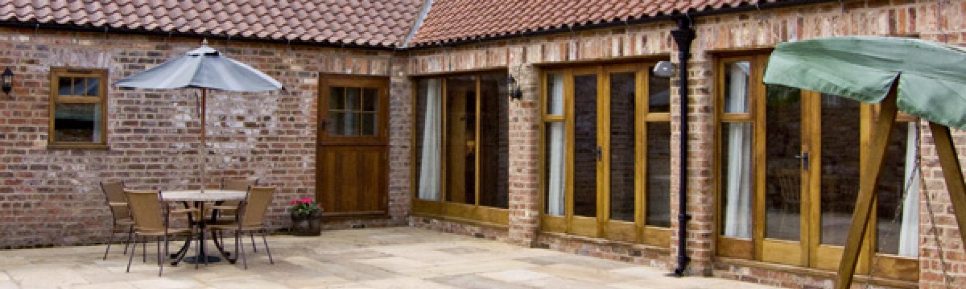 A courtyard barn conversion with a frontage comprising wall-to-ceiling French windows.