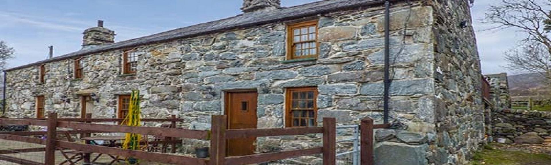 An end-terrace stone-built Gwynedd holiday cottage with a paved, secure front patio.