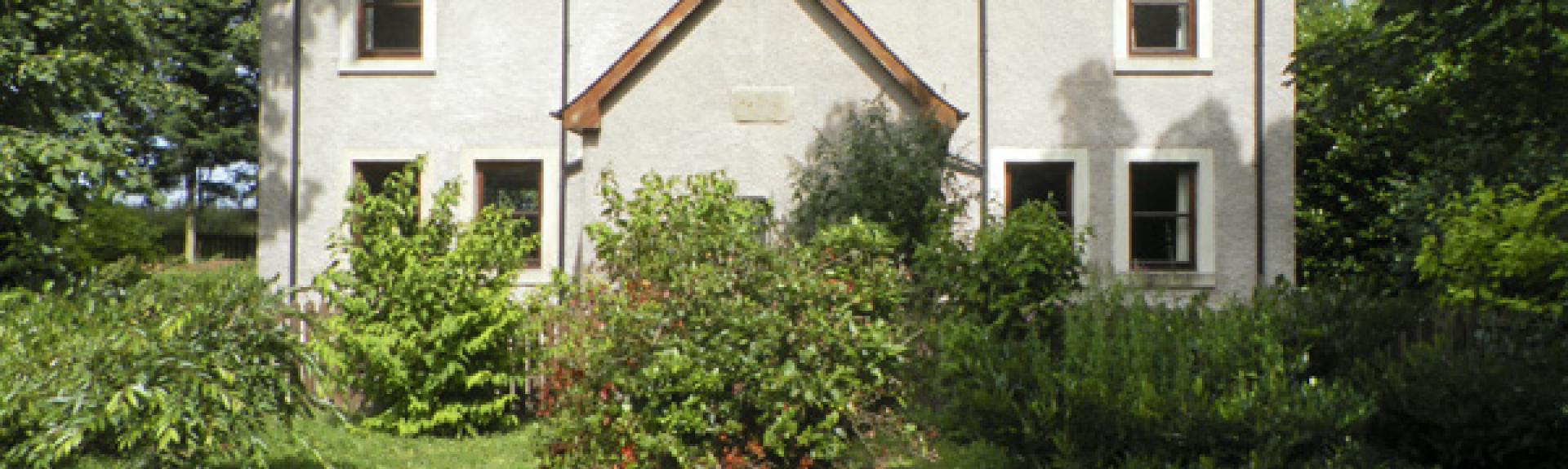Adouble-fronted holiday cottage witha covered porch overlooks a mature front garden.