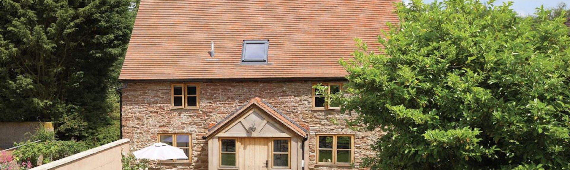 A stone-built cottage with enclosed porch overlooks a secure lawned garden