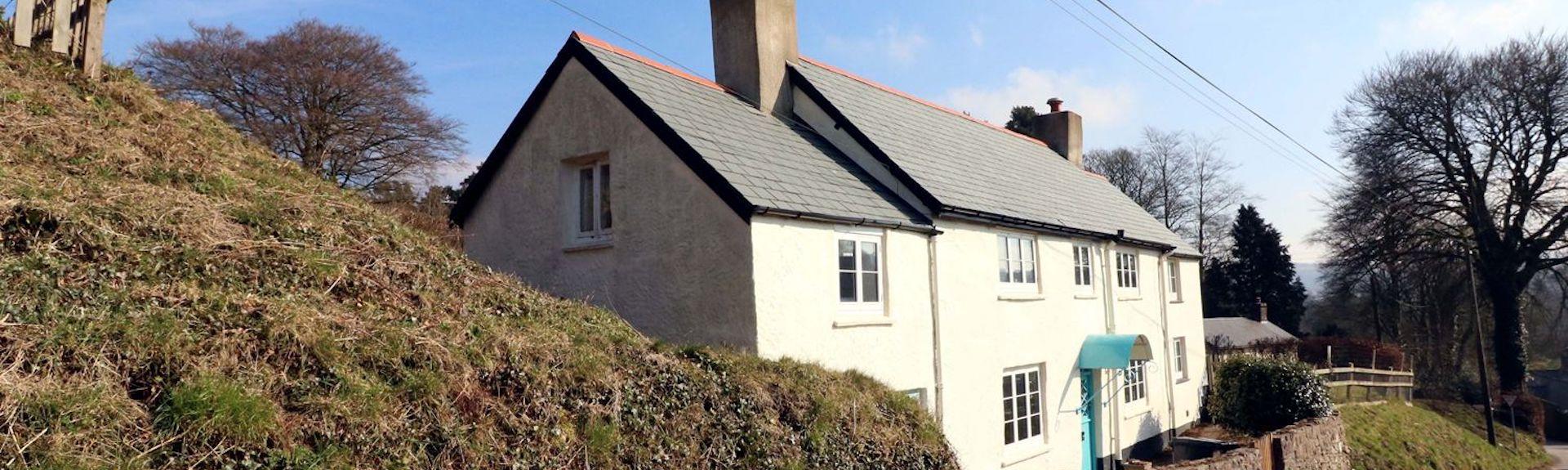 An Exmoor Longhouse overlooks a quiet, steep-banked country lane