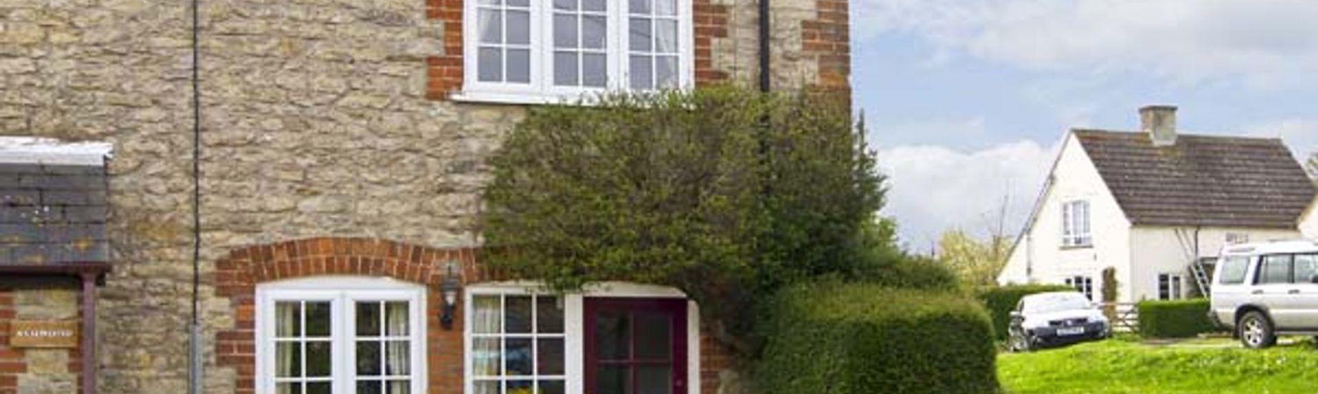 A semii-detached Dorset cottage overlooks a paved front courtyard for parking.