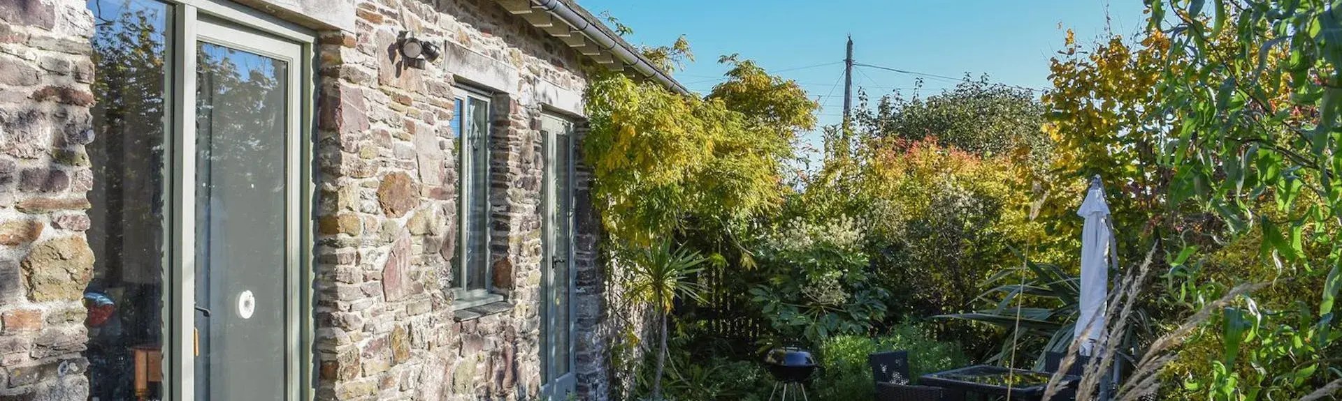 A single storey barn conversion with Frenchwindos and a mature garden of shrubs and small trees.