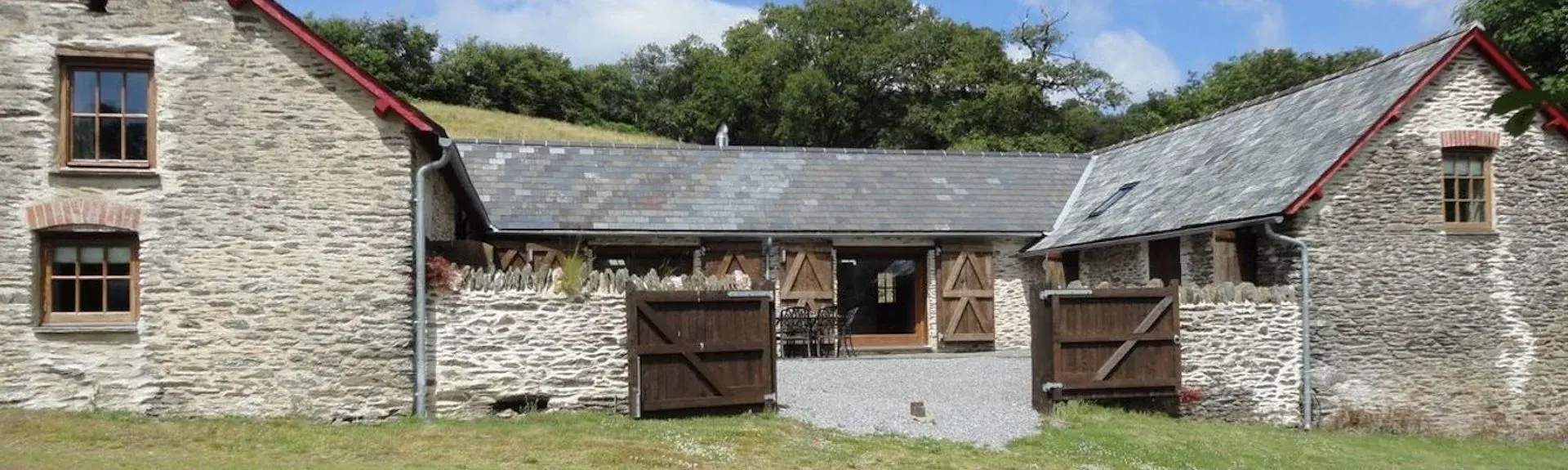 A twin-gabled Exmoor barn conmverion surounded by a lawn.