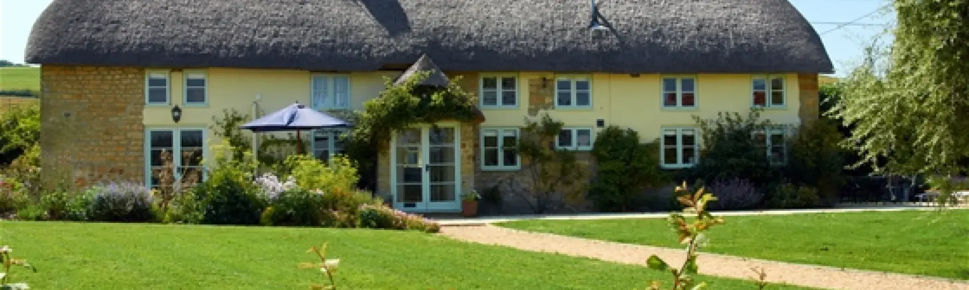 A large thatched cottage overlooking a spacious lawn near Bridport.