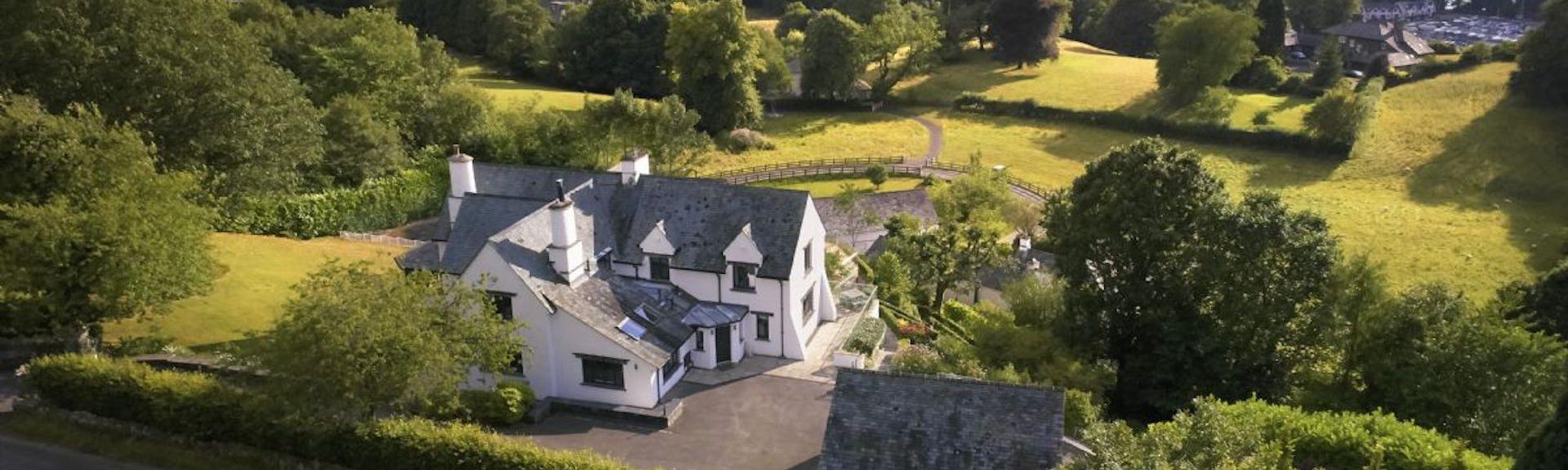 Aerial view of a holiday cottage surrounded by fields overlooking Lake Windermere.