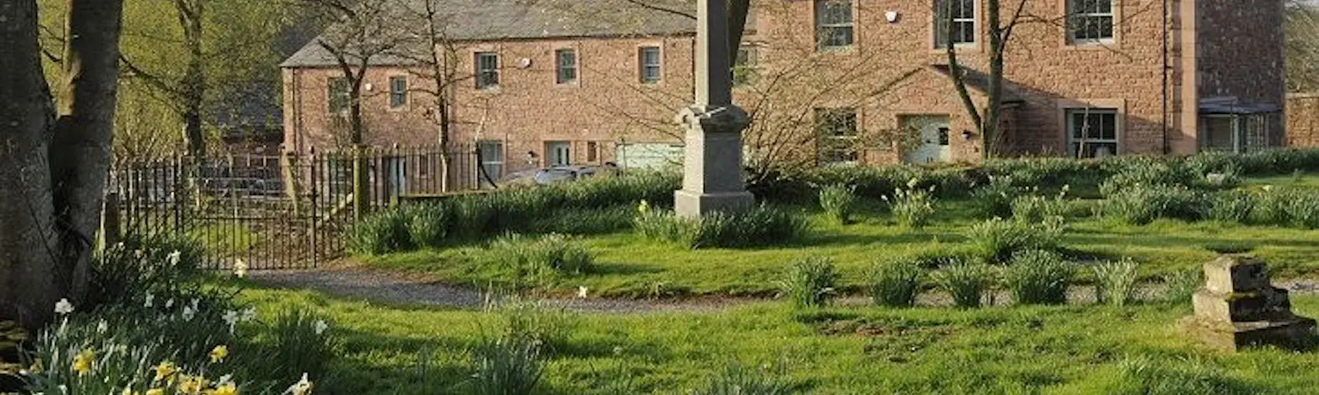 Exterior of a large country house surrounded by lawned gardens.