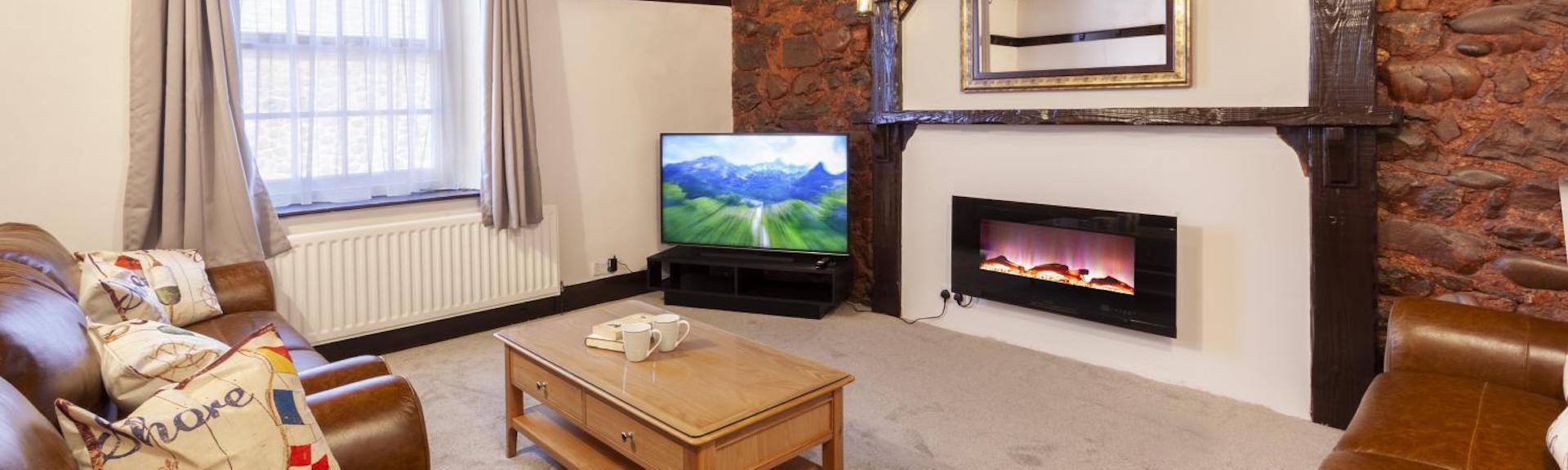 An oak beamed lounge with woodburner, wide-screen TV and a comfy sofa.