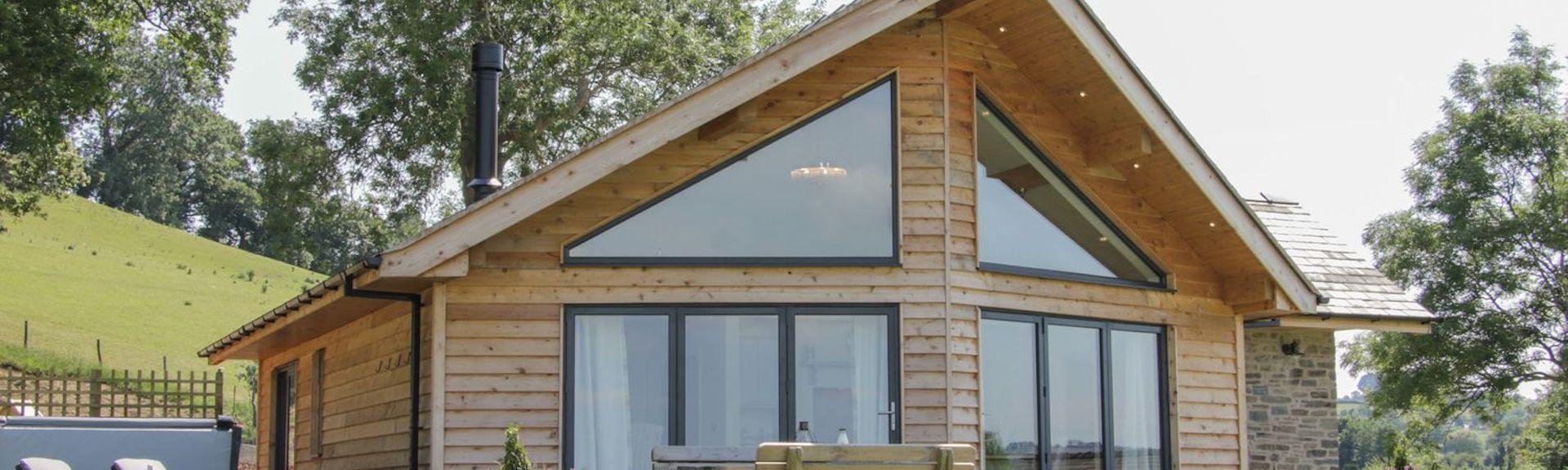 Gable end of a contemporary wooden lodge in Powys with floor-to-ceiling windows