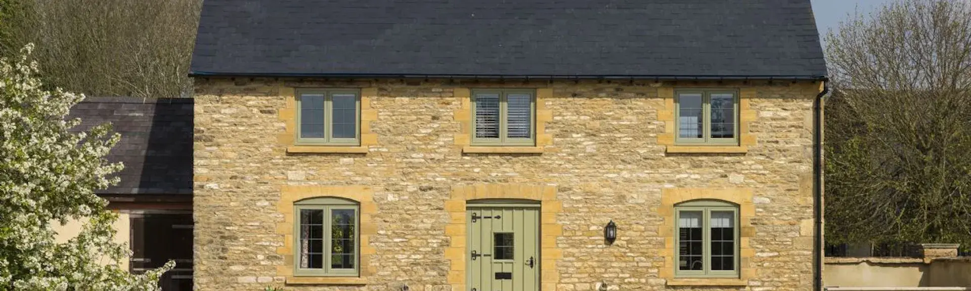 Exterior of a double-fronted Cotwolds honey-stone cottage