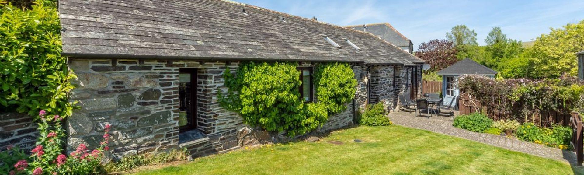 A single-storey stone barn conversion in Polzeath sits alongside a large lawn.