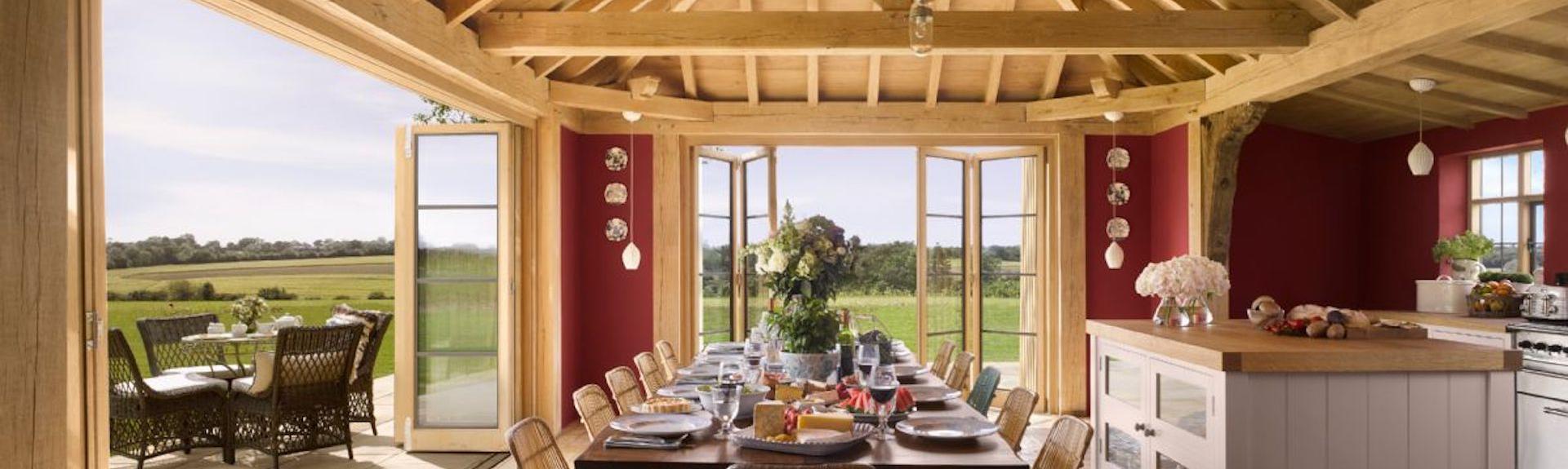 A dining table for 12 is laid for dinner under the oak beams of a country cottage kitchen