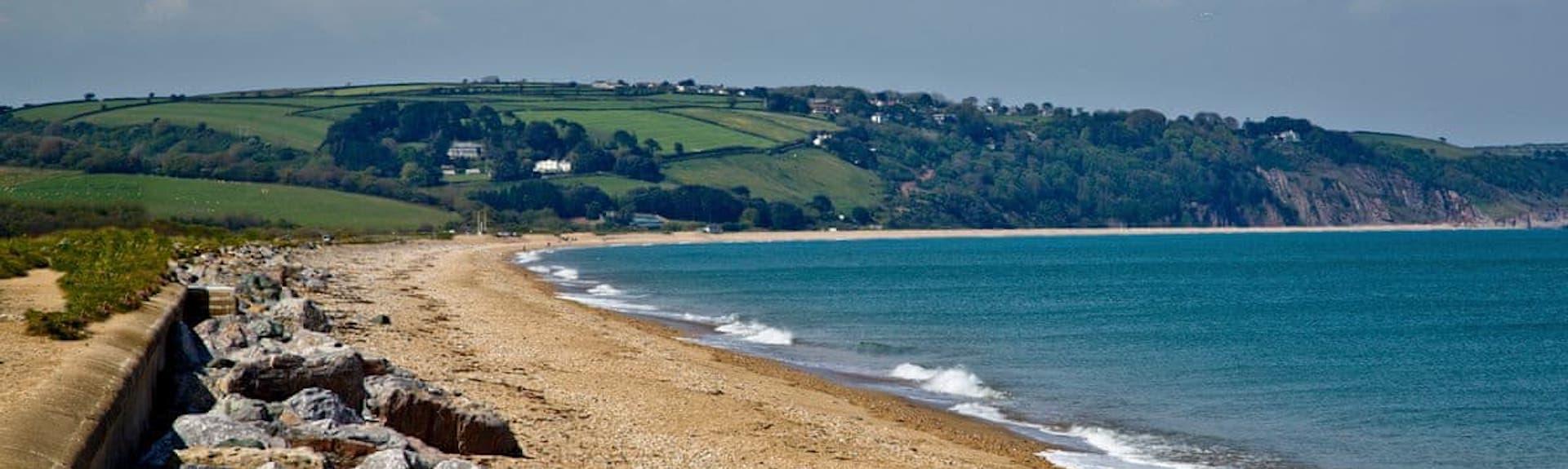 The long and sandy Slapton beach with a calm sea at high tide.