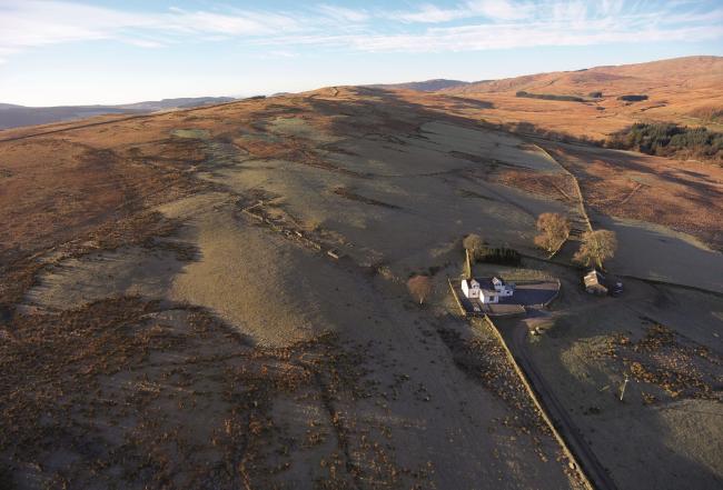 Corriedow Holiday Cottage in Thornhill. An aerial view of a small farm in a remote Scottish Glen and outbuildings in autumn sunlight.
