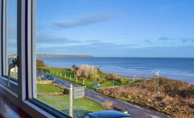 Sea Views From Beach Villa in Filey A sea view through a window at Beach Villa with a lawn, road, bracken and the sea beneth a clear sky.
